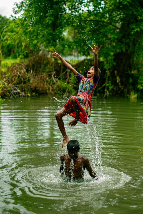 Free Two children splash playfully in a river, capturing the essence of childhood joy. Stock Photo
