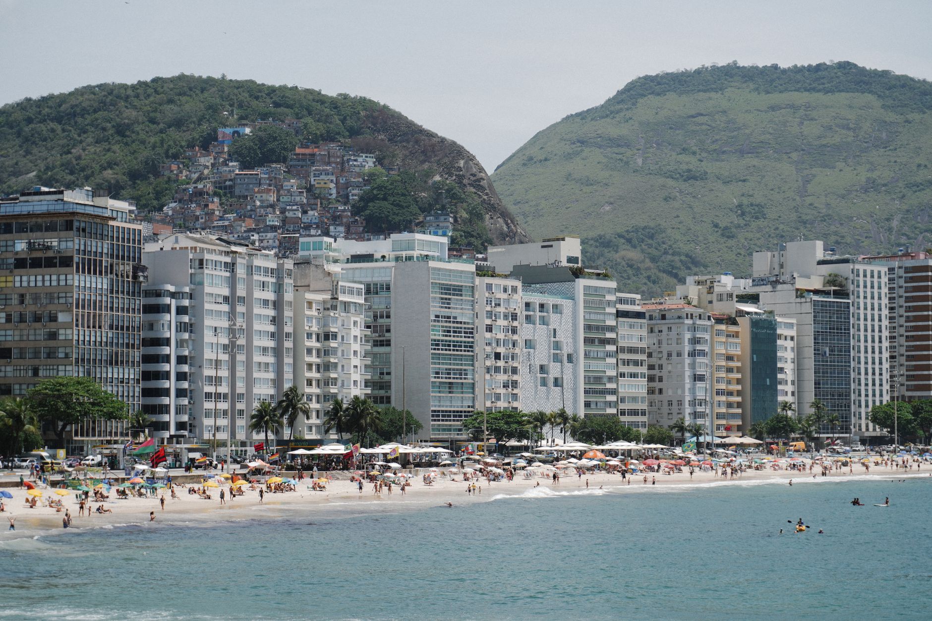 A vibrant scene at Copacabana Beach showing buildings and lively beachgoers under sunny skies.