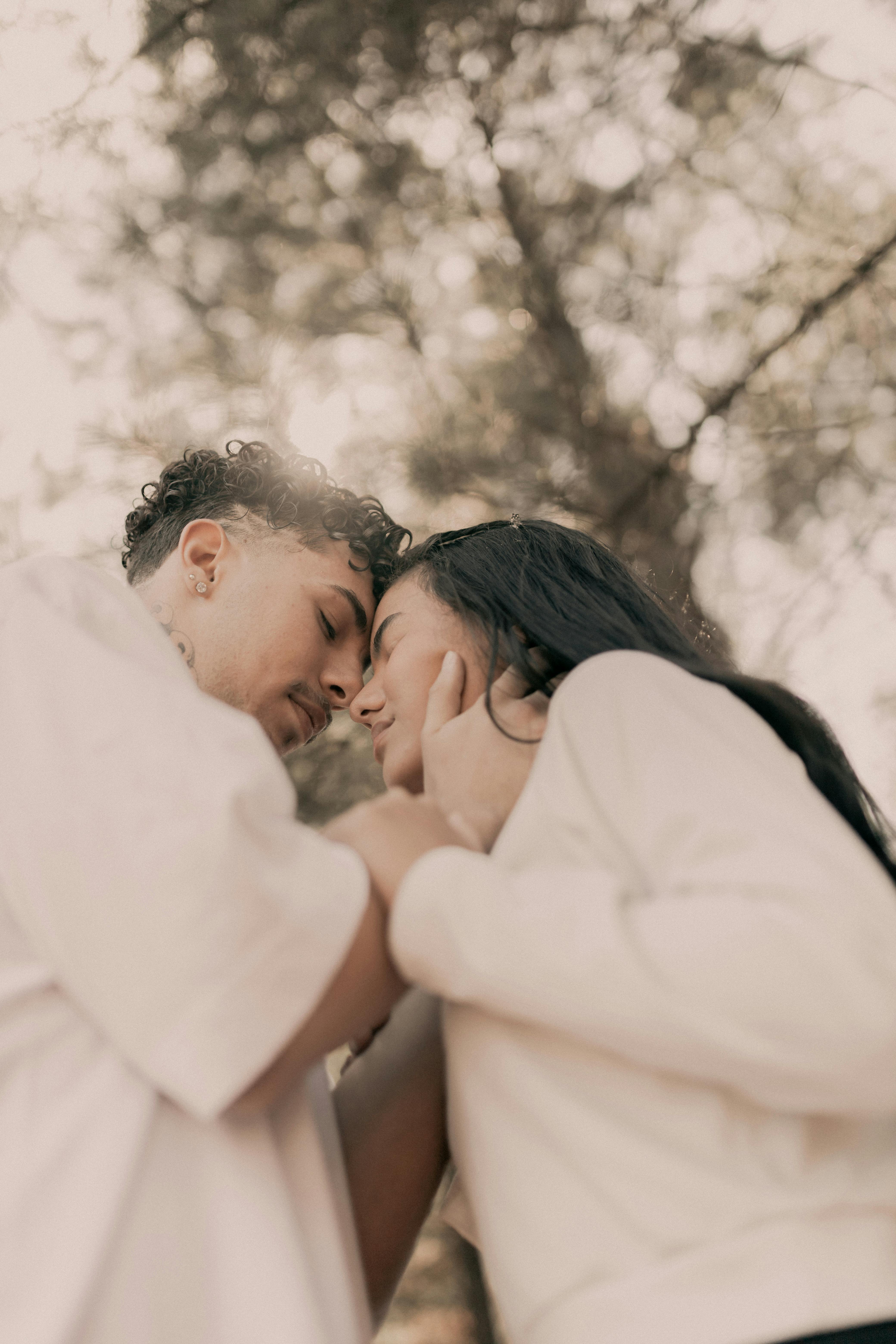 Intimate couple in soft embrace, rain-streaked window in background, moody autumn atmosphere of deep connection and surrender