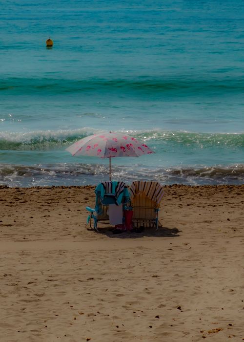 Free Peaceful beach scene in El Campello, Spain with chairs and umbrella, perfect for relaxation. Stock Photo