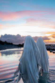Mysterious ghostly figures walking along a serene Hawaiian beach at sunset.