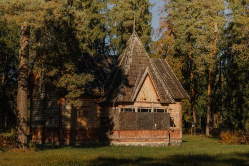 Free Charming wooden cabin with pointed roof nestled in a sunlit forest clearing. Stock Photo