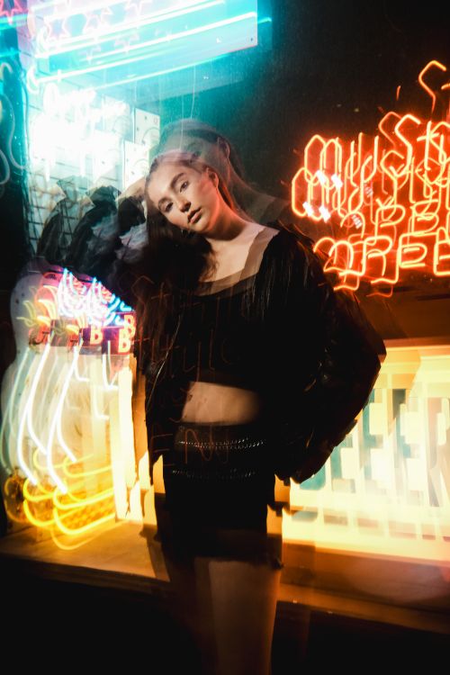 Free Stylish woman posing amid vibrant neon lights reflecting nightlife energy. Stock Photo