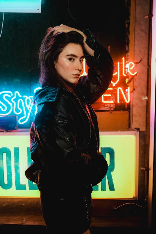 Free Stylish woman poses in front of vibrant neon signs, creating a moody urban aesthetic. Stock Photo