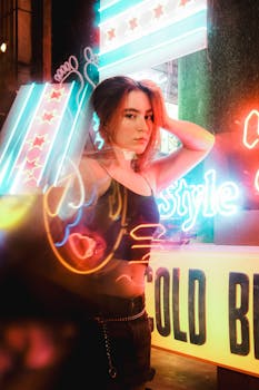 Stylish model posing under vibrant neon lights in an urban scene at night.