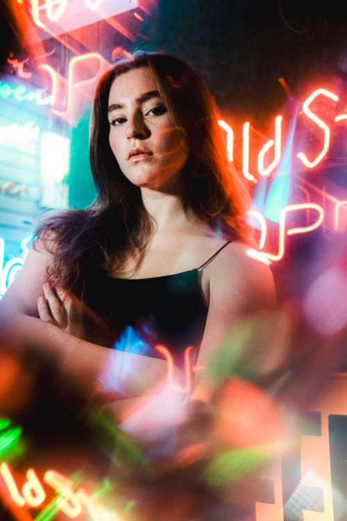 Free Young woman posing confidently against a vibrant neon backdrop. Stock Photo