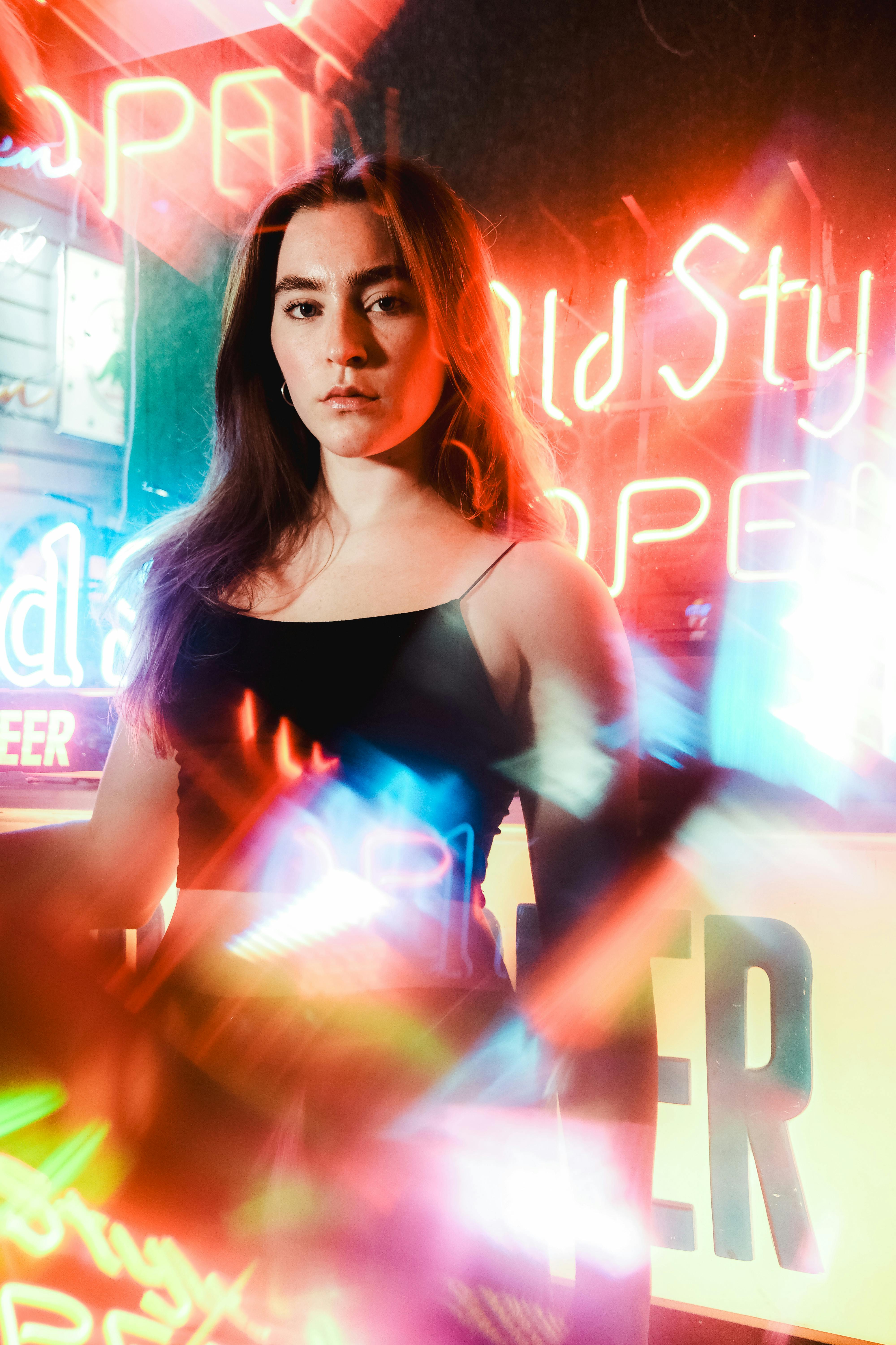 Dynamic portrait of a woman surrounded by vibrant neon lights, creating a colorful and modern urban ambiance.