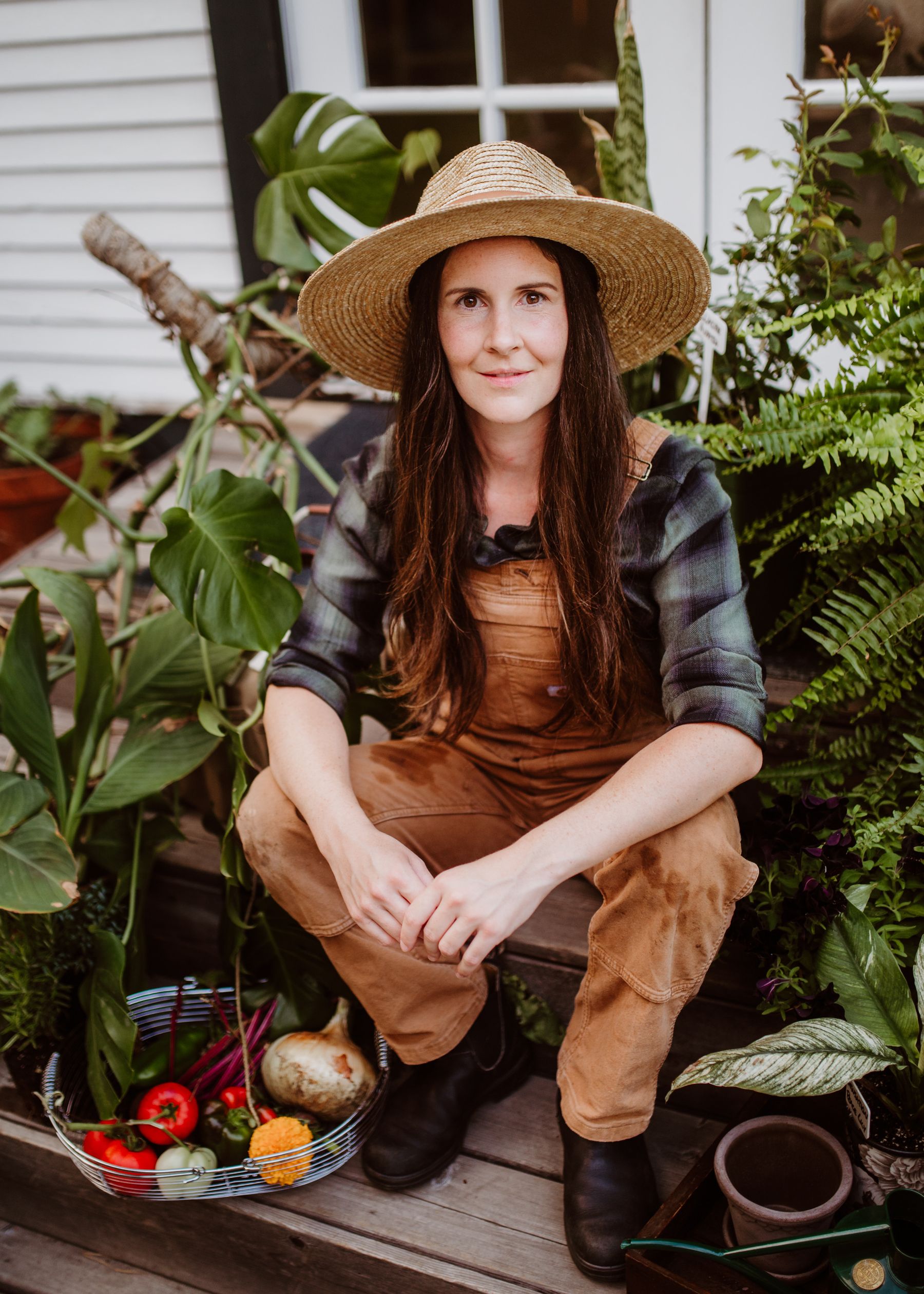 A gardener with freshly harvested vegetables in a garden A gardener with freshly harvested vegetables in a garden