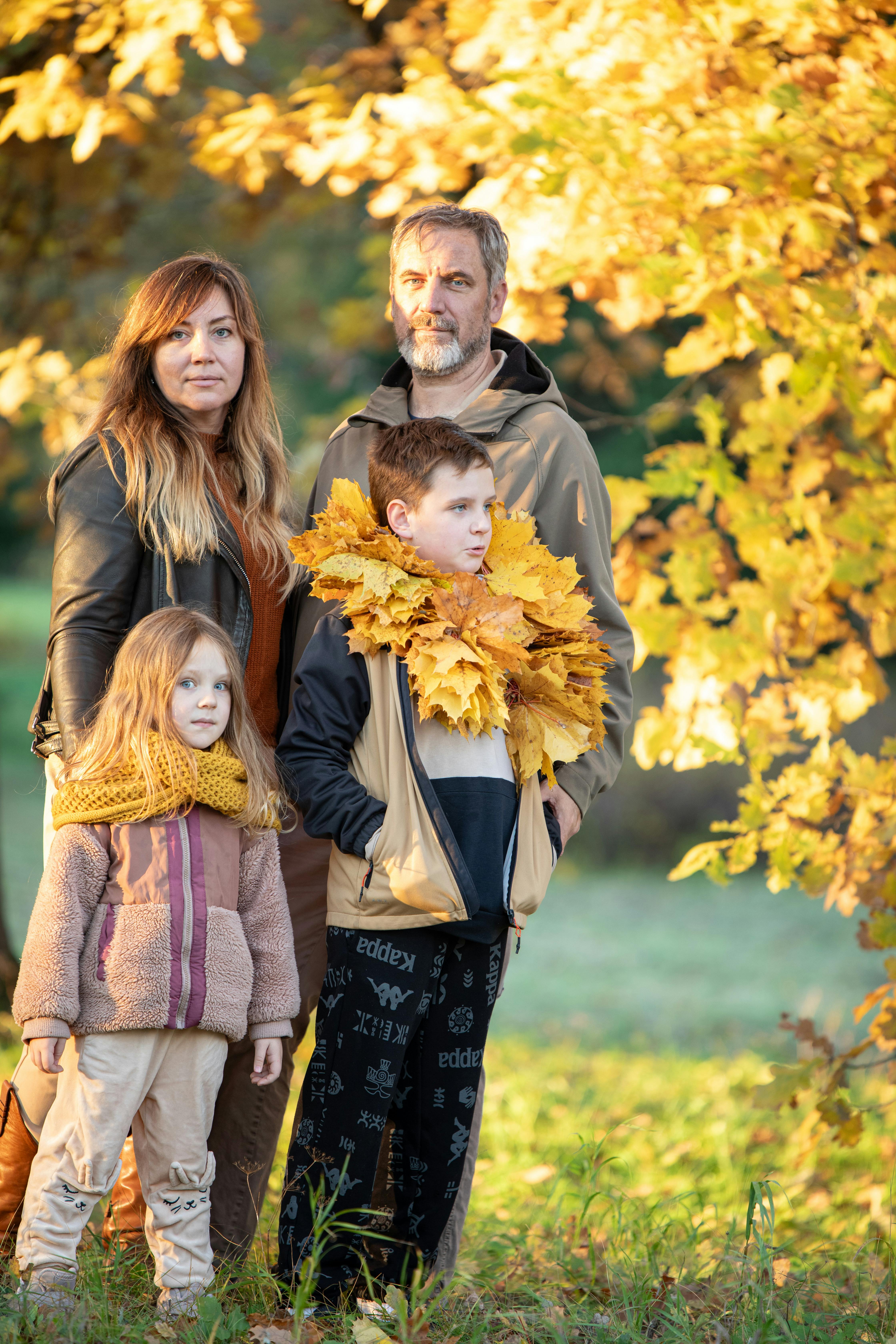 A family enjoys a warm autumn day surrounded by vibrant foliage in a park.