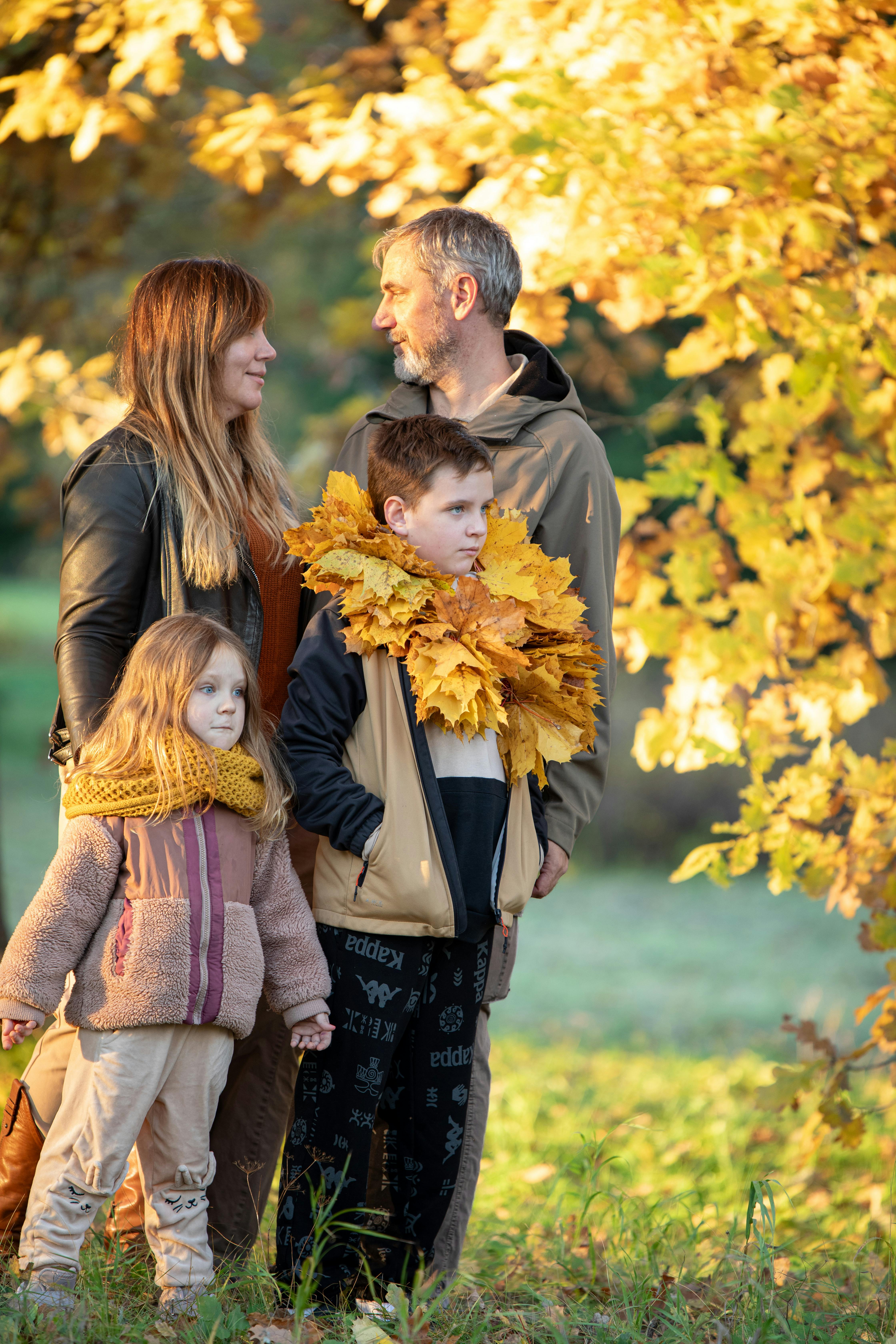 Family portrait in park surrounded by golden autumn leaves, capturing joyful seasonal moments.