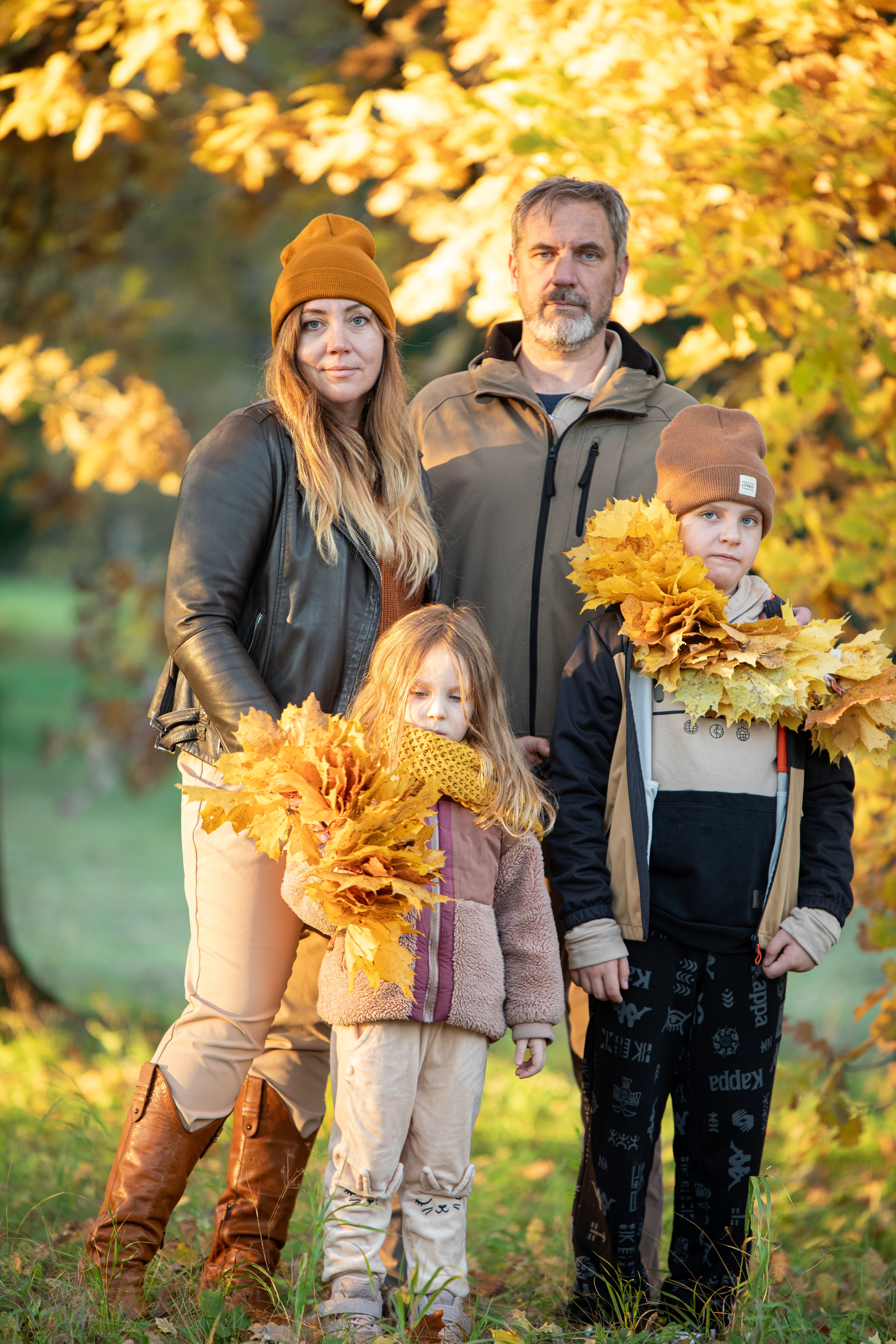 A family enjoying a beautiful autumn day with fall leaves in a park setting.