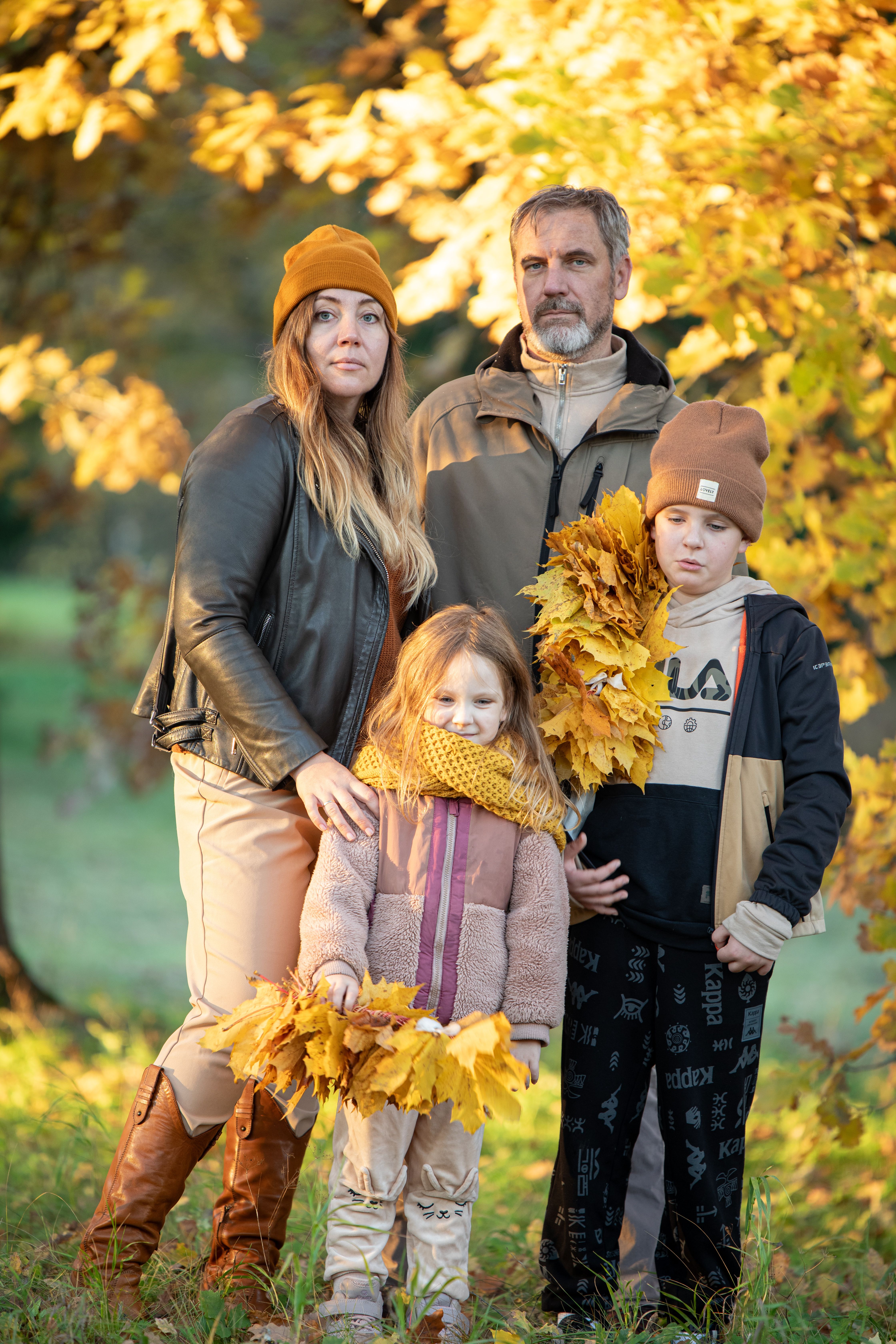 Happy family portrait with autumn leaves in a park, showcasing fall fashion and seasonal mood.