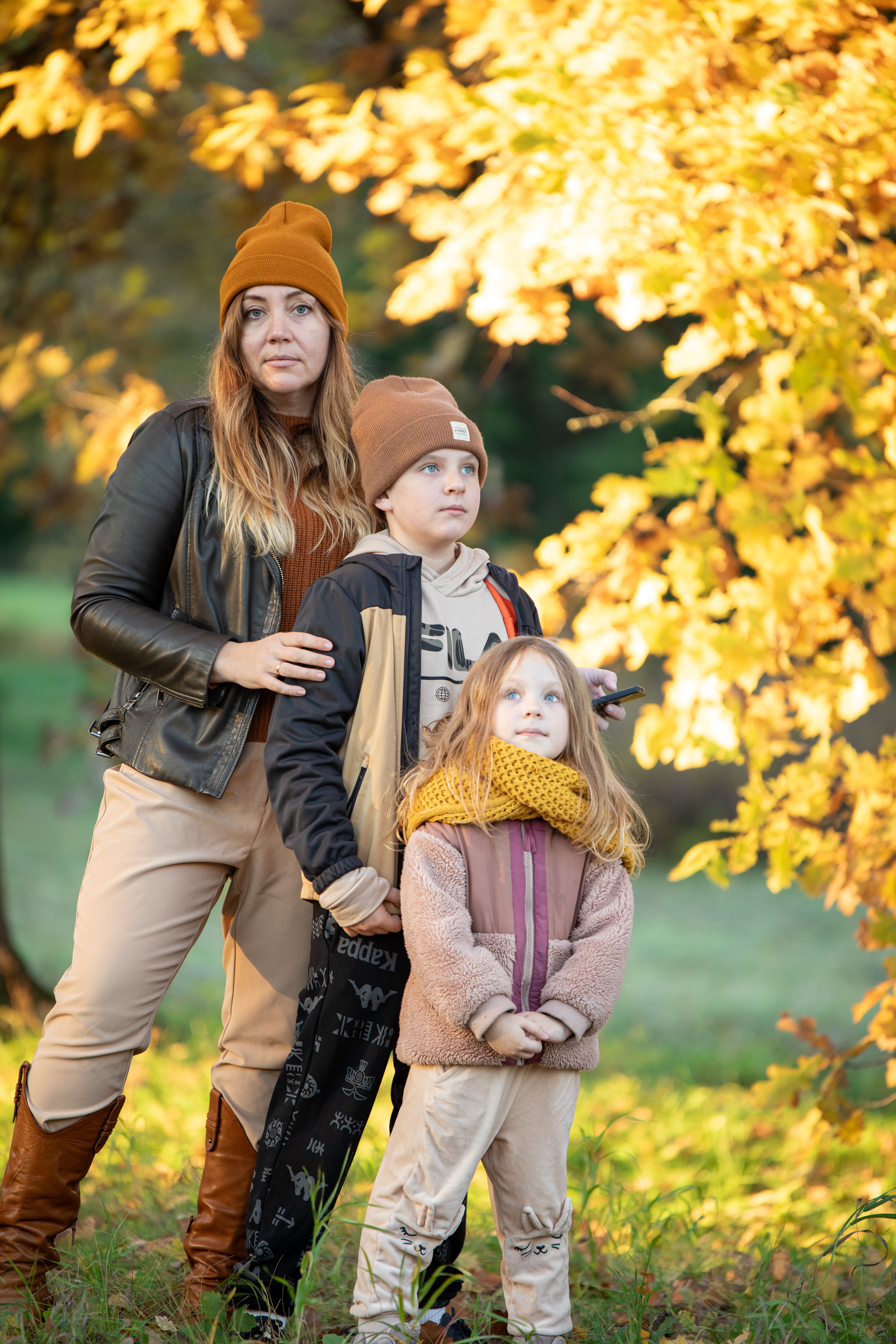 Family posing together during a beautiful autumn day surrounded by golden leaves.