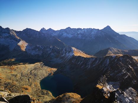 Captivating aerial view of a mountain range with a lake, captured during sunrise, showcasing nature's stunning beauty.