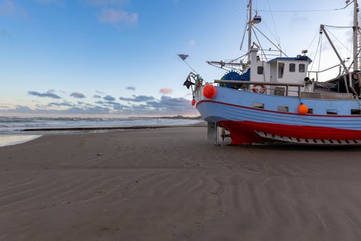 A vibrant fishing boat rests on the sandy beach of Løkken, Denmark, with a serene ocean backdrop.