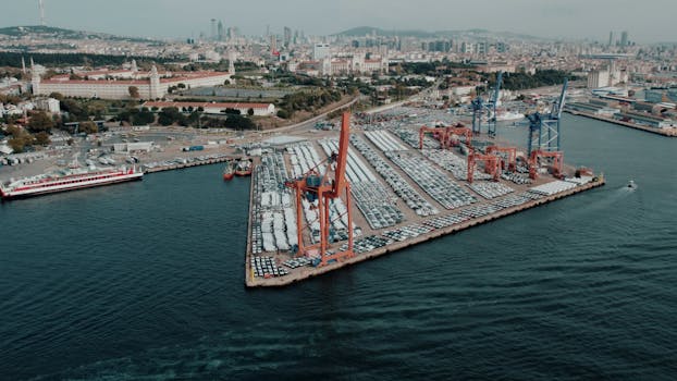 Aerial view of a busy cargo port in Istanbul with cityscape in the background, highlighting logistics and trade.