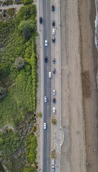 Stunning aerial view of a beachside road in Muscat, Oman, highlighting the natural and urban landscapes.