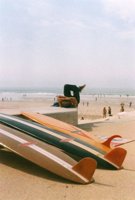 Colorful surfboards and sunbathers on a sunny day at Figueira da Foz beach, Portugal.