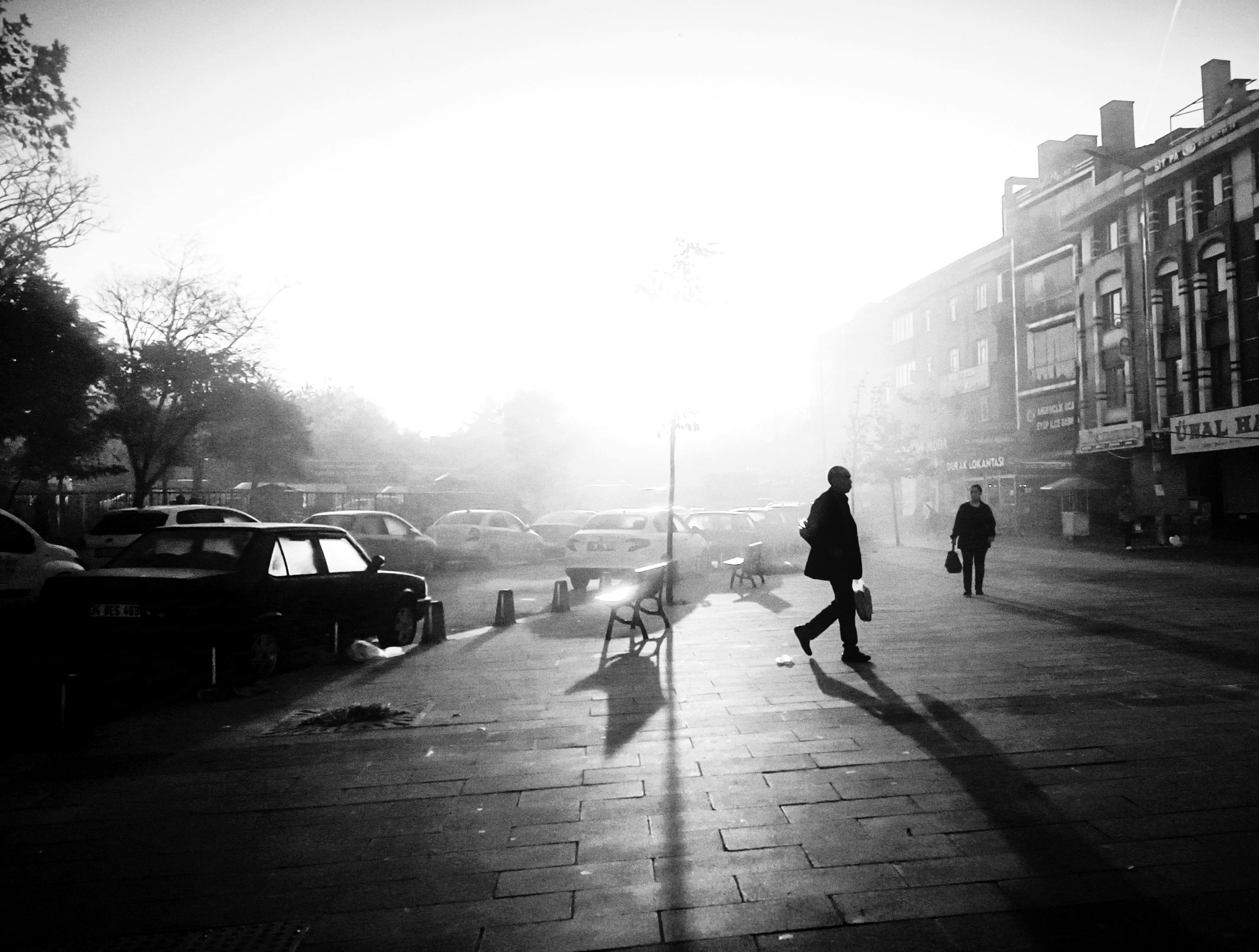 Silhouettes of people walking on a misty street in Istanbul, capturing urban life and atmosphere.