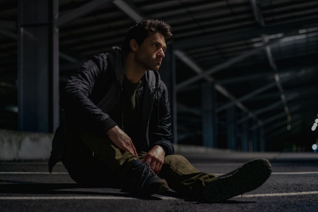 thoughtful man sitting under a bridge at night deep in reflection
