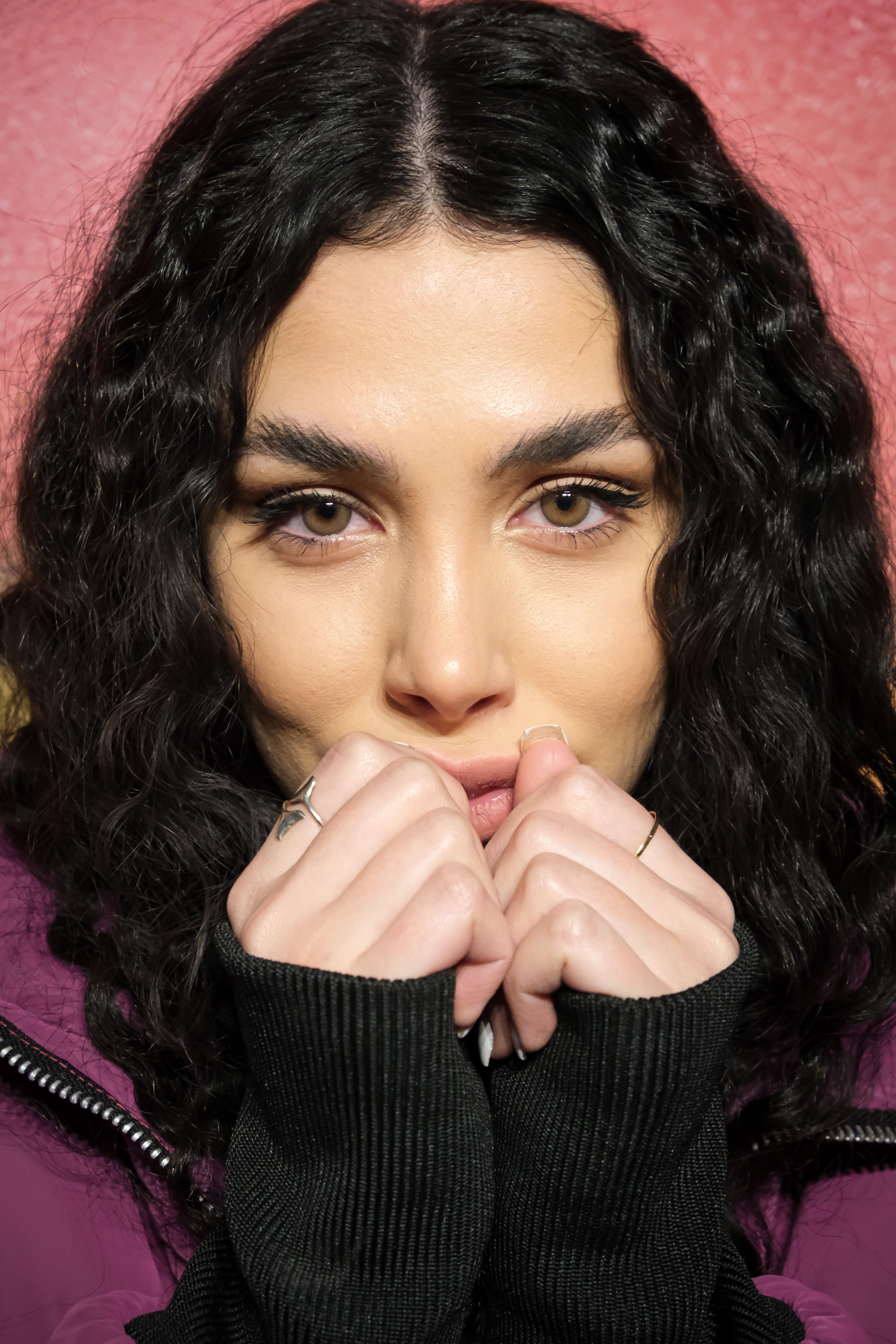 Bright portrait of a woman with curly hair, cozying up in a winter jacket.