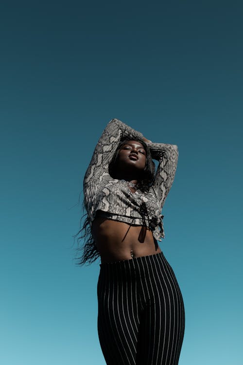 Photo of Woman Snakeskin Long-sleeved Crop-top Posing  With Her Eyes Closed and Her Arms Raised
