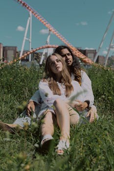 一对年轻夫妇在科尼岛公园享受阳光明媚的一天，背景是过山车