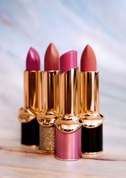 A stylish display of luxury lipsticks with gold accents on marble background.