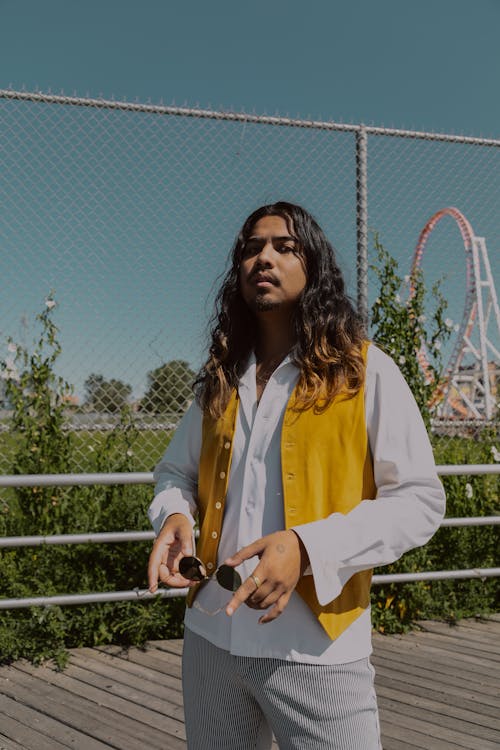 Photo of Man With Long Hair Posing While Holding Sunglasses