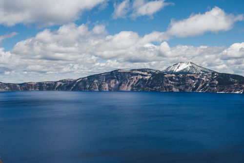 Free Breathtaking view of a snow-capped mountain with a tranquil blue lake beneath and a vast sky overhead. Stock Photo