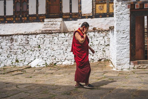 Monk Holding Smartphone Outside Concrete Building