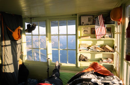 Warm interior of a mountain cabin with books, gear, and a scenic view through windows in Darrington, WA.