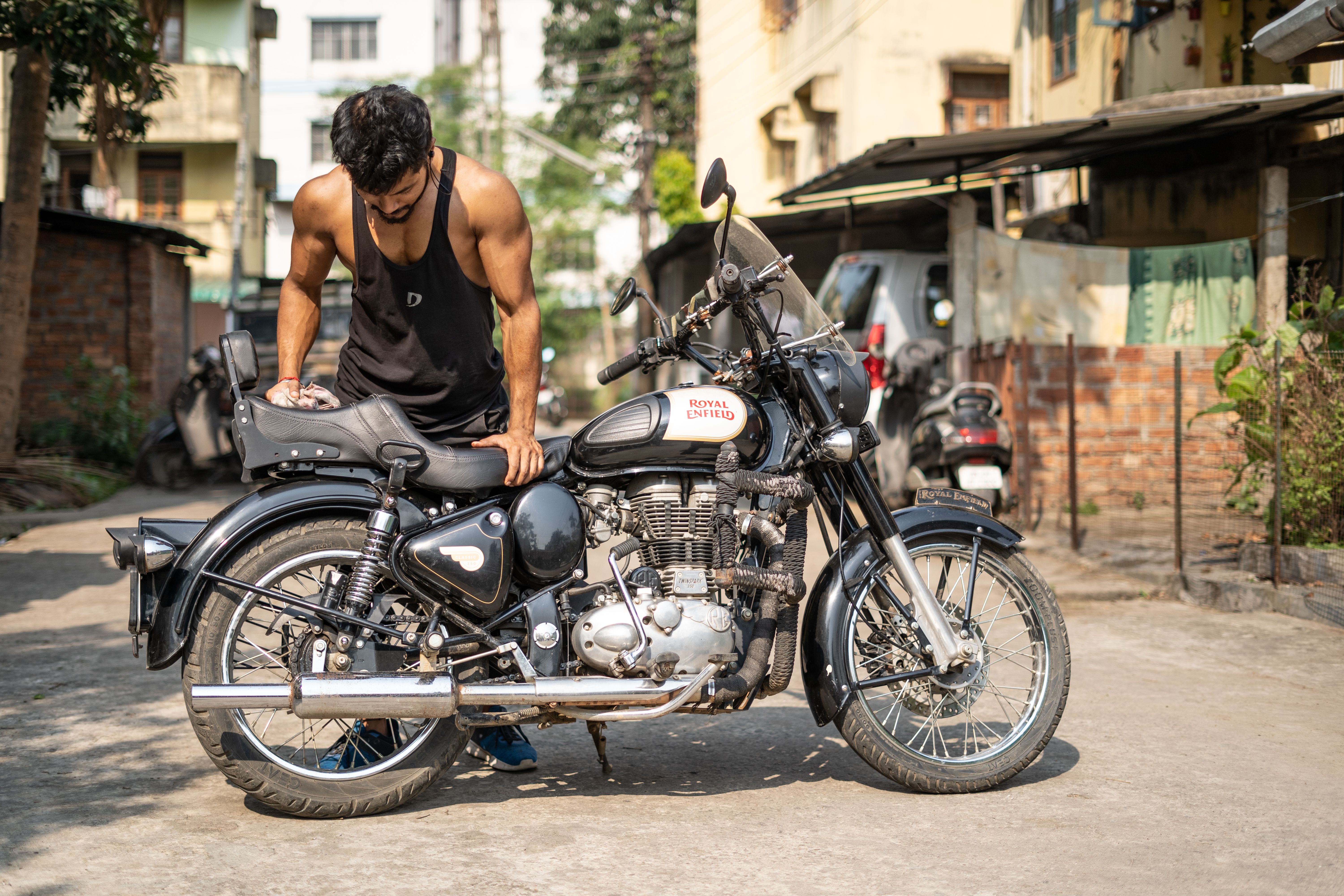 Man Inspecting Royal Enfield Motorcycle Outdoors · Free Stock Photo
