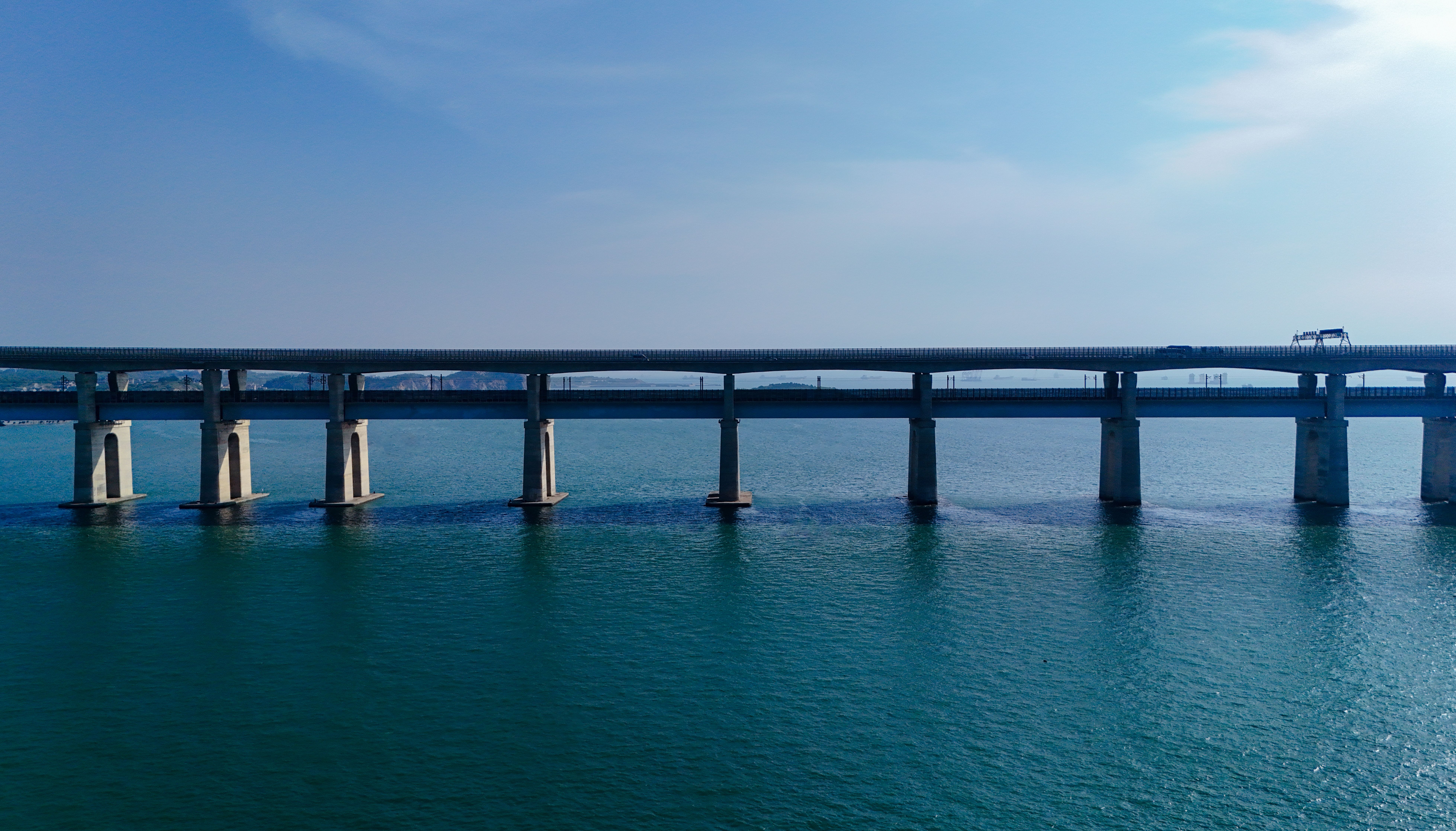 Long bridge spanning across a calm blue lake · Free Stock Photo