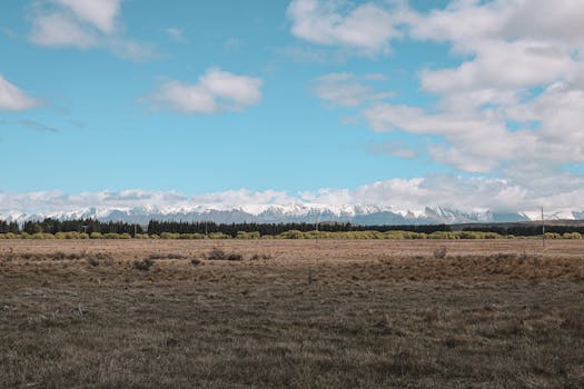 Breathtaking landscape of snow-capped mountains and open fields in Queenstown, New Zealand.