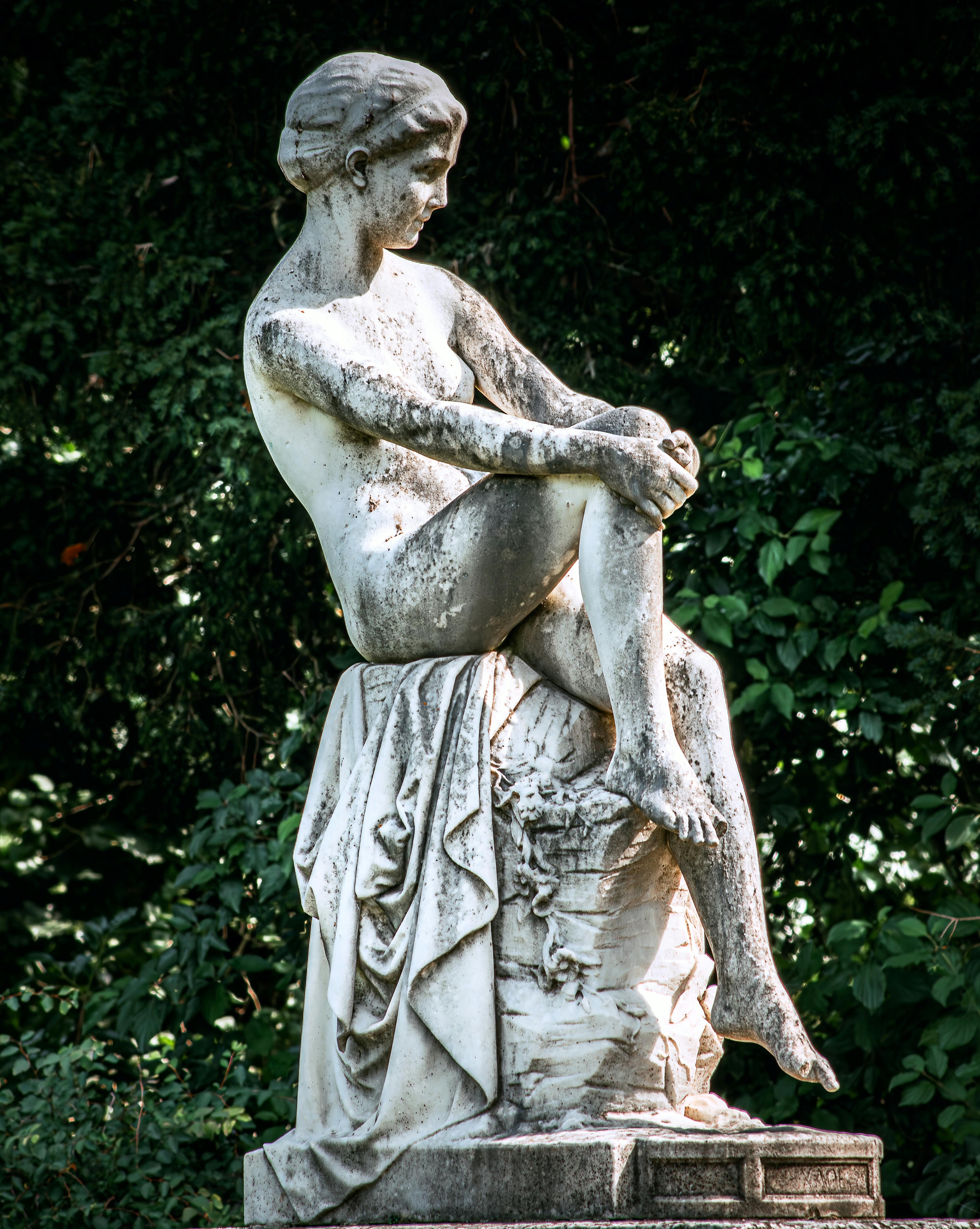 A magnificent marble statue surrounded by lush green foliage, exuding timeless elegance.
