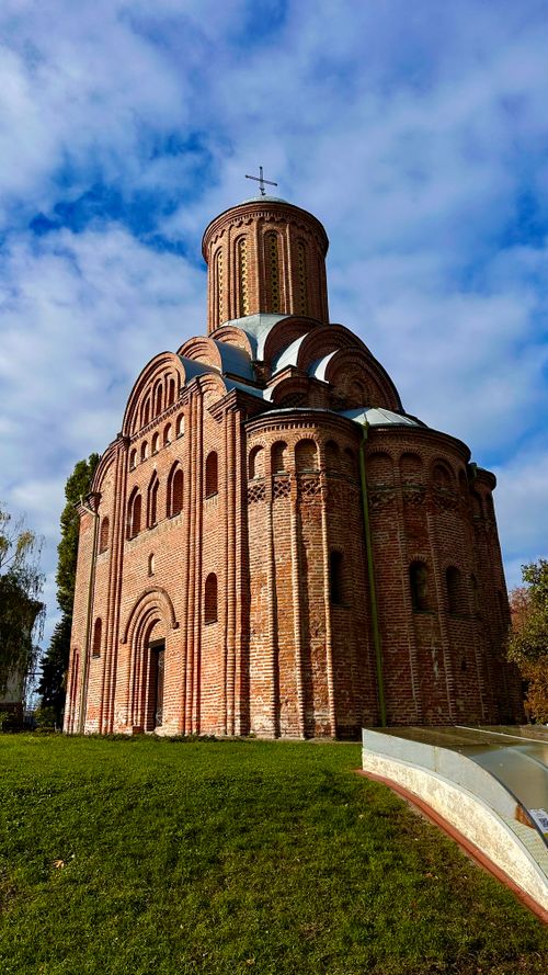 Free A beautiful ancient brick church under a bright blue sky, surrounded by greenery. Stock Photo