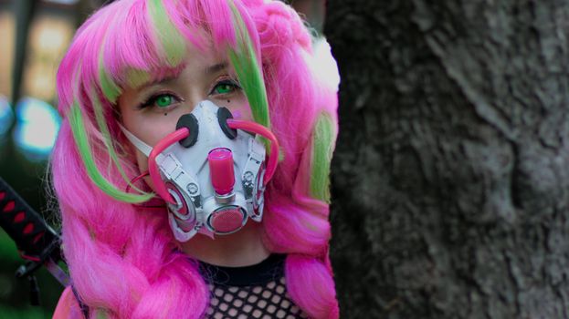 A captivating anime-inspired cosplay with pink hair and a gas mask in an outdoor setting.