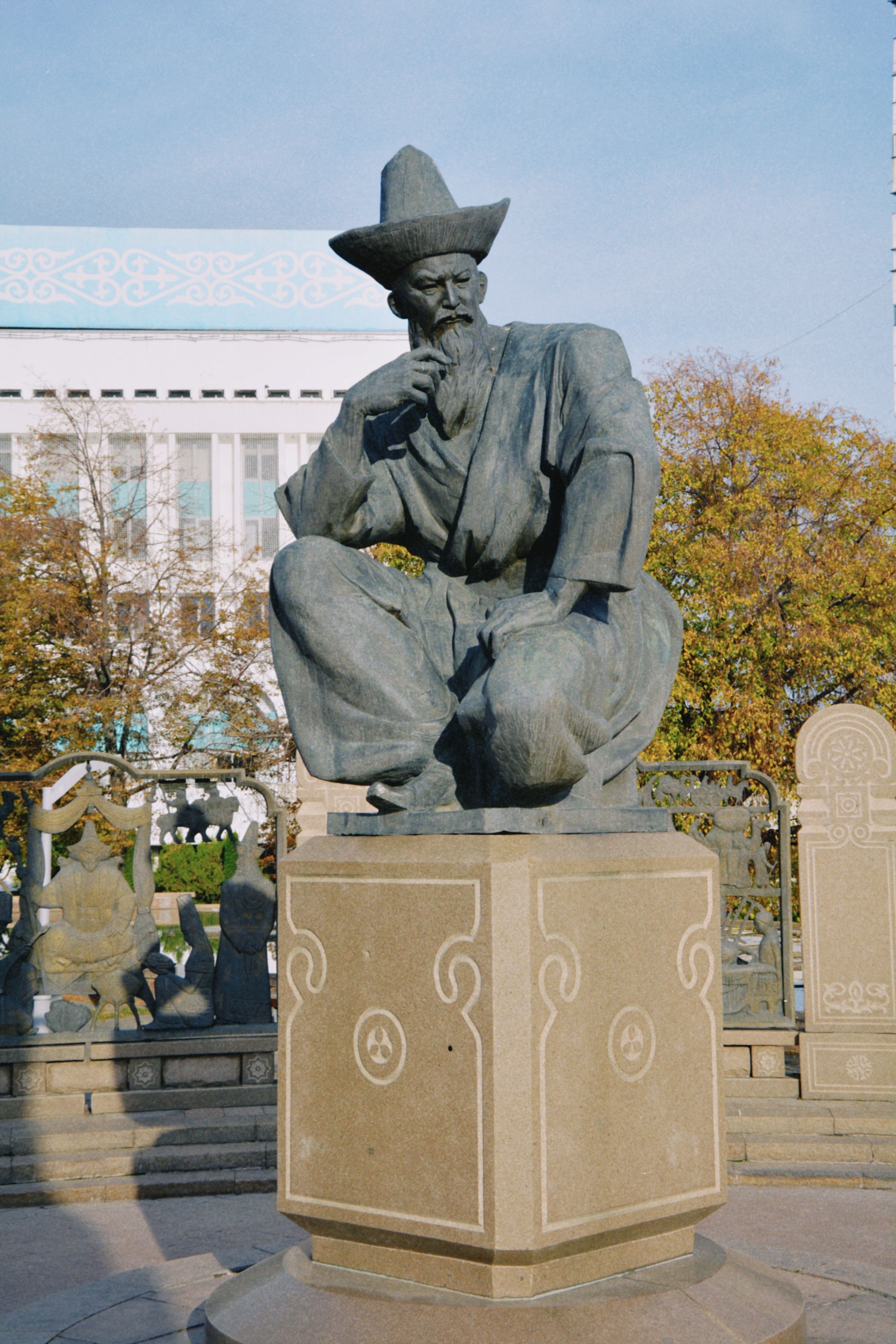 A prominent statue of a historical Kazakh figure in the center of Almaty, Kazakhstan during the day.