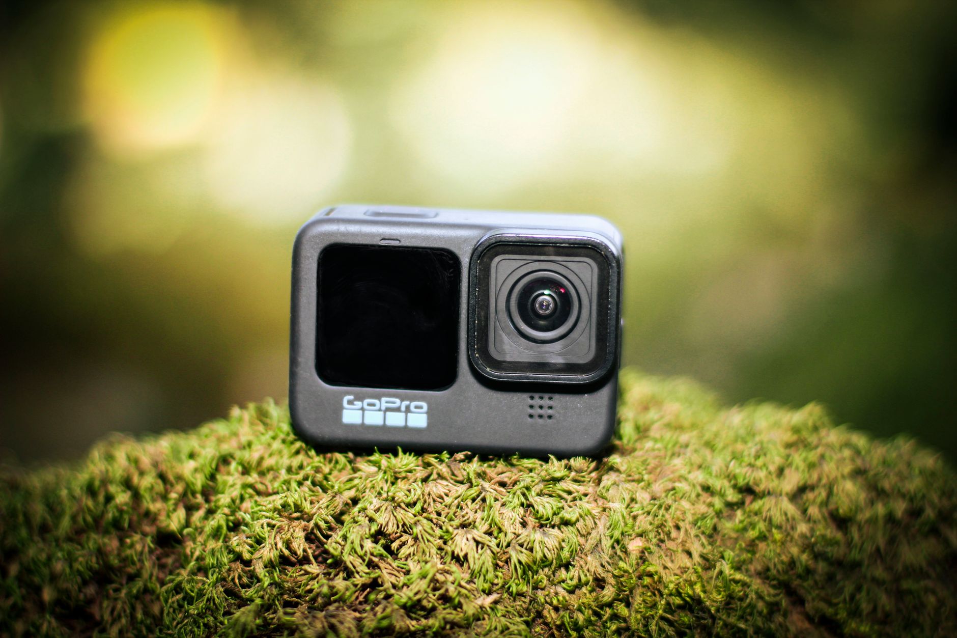A GoPro camera placed on lush moss, captured in vibrant natural lighting outdoors.