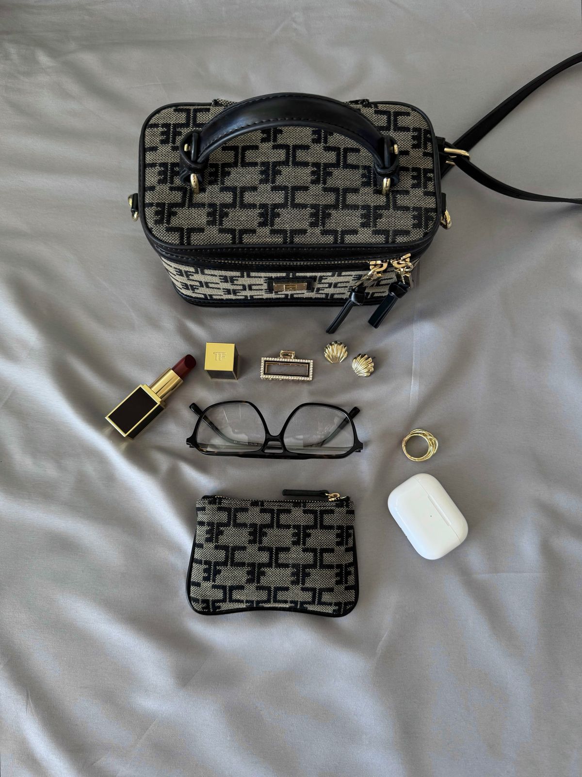 A curated arrangement of fashion accessories, jewelry, sunglasses, and a handbag