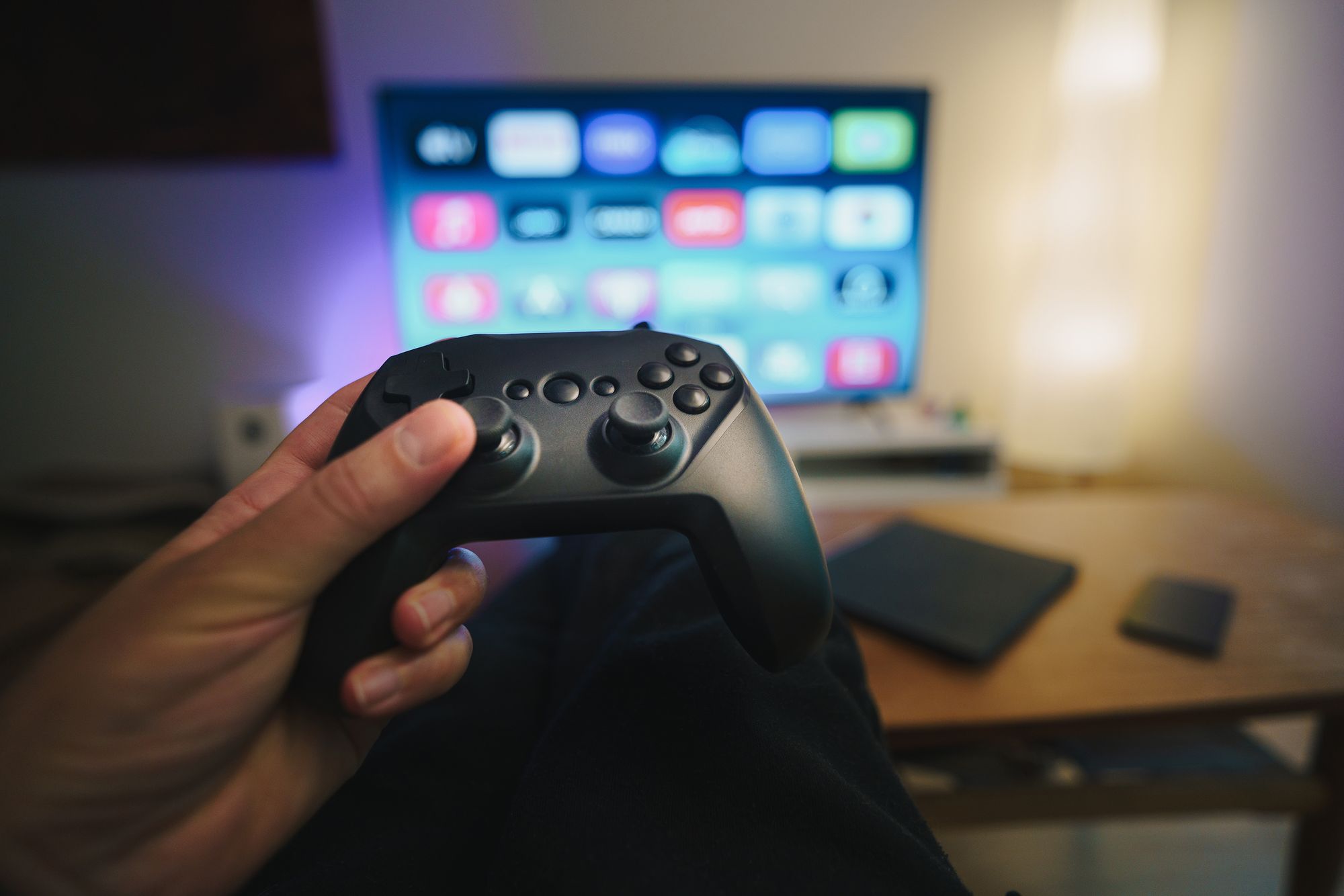 Control de videojuegos sobre un sillón frente a una pantalla de televisión encendida en una sala de estar