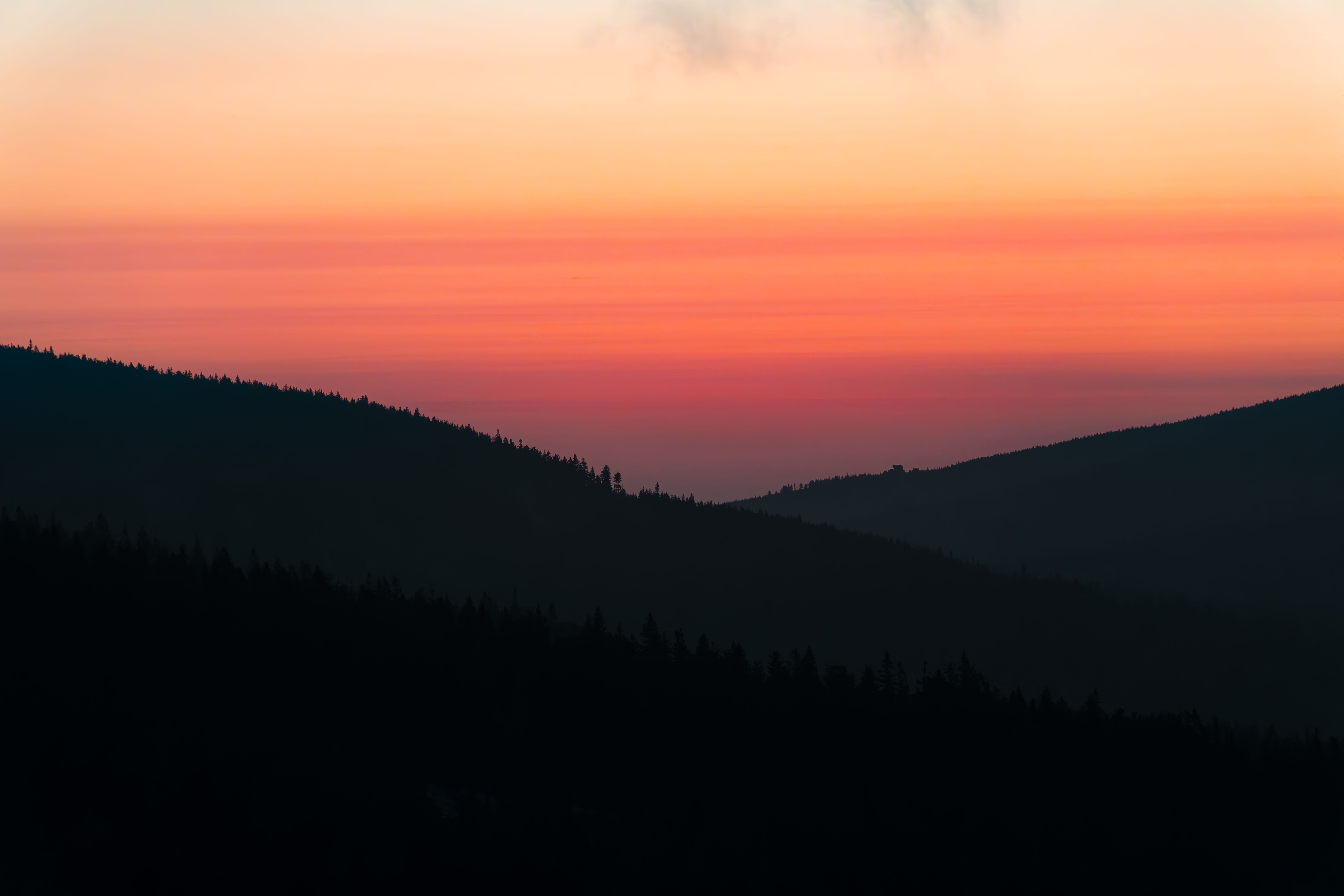 A tranquil sunrise over the rolling hills of Szklarska Poręba, Poland, showcasing vibrant hues and peaceful landscape.