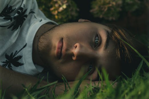 一个年轻人躺在草地上，若有所思地凝视着远方
