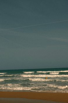Peaceful ocean waves gently crashing onto a sandy beach under a clear sky.