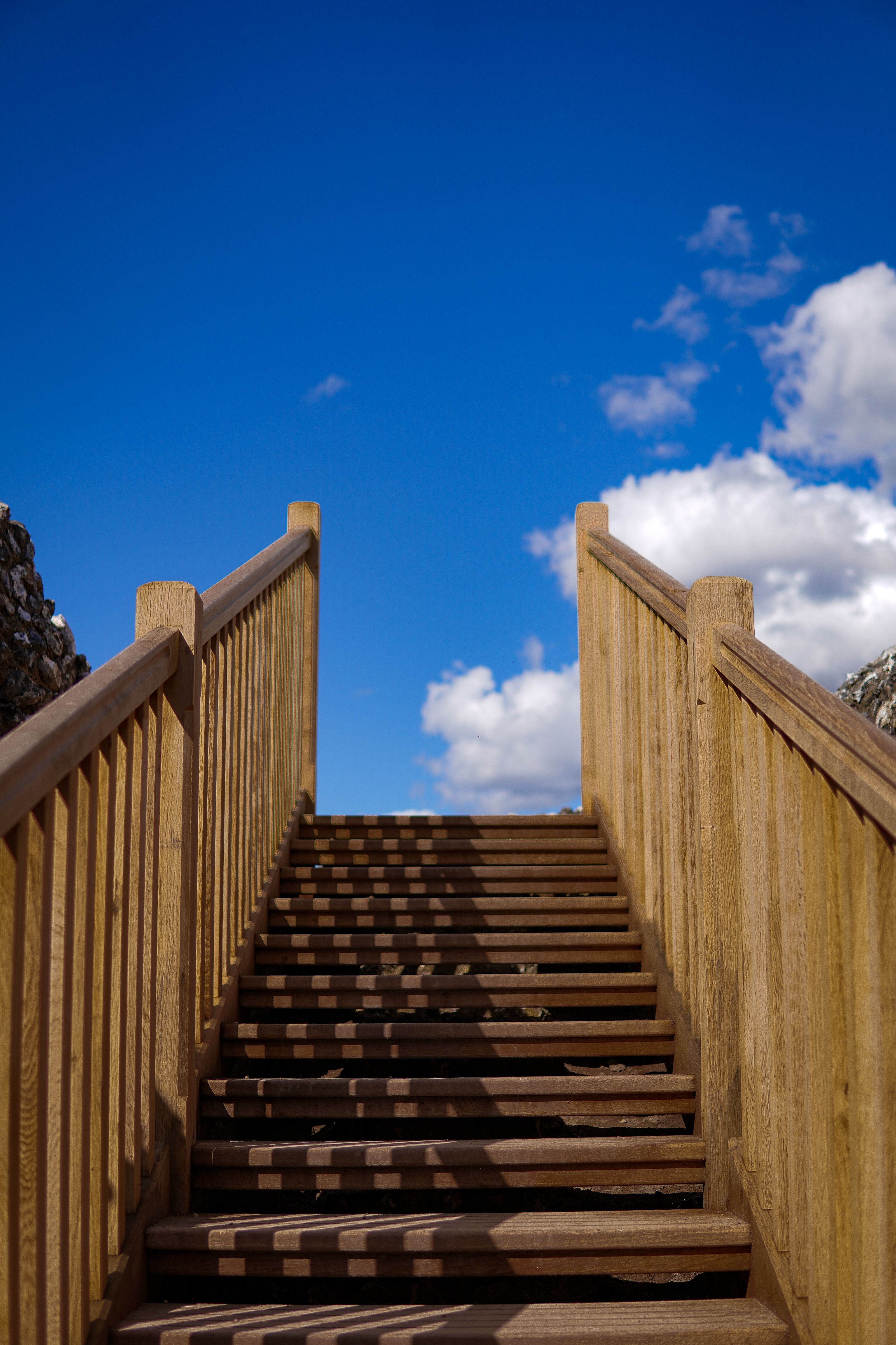Escalera de madera ascendiendo hacia un cielo azul con nubes