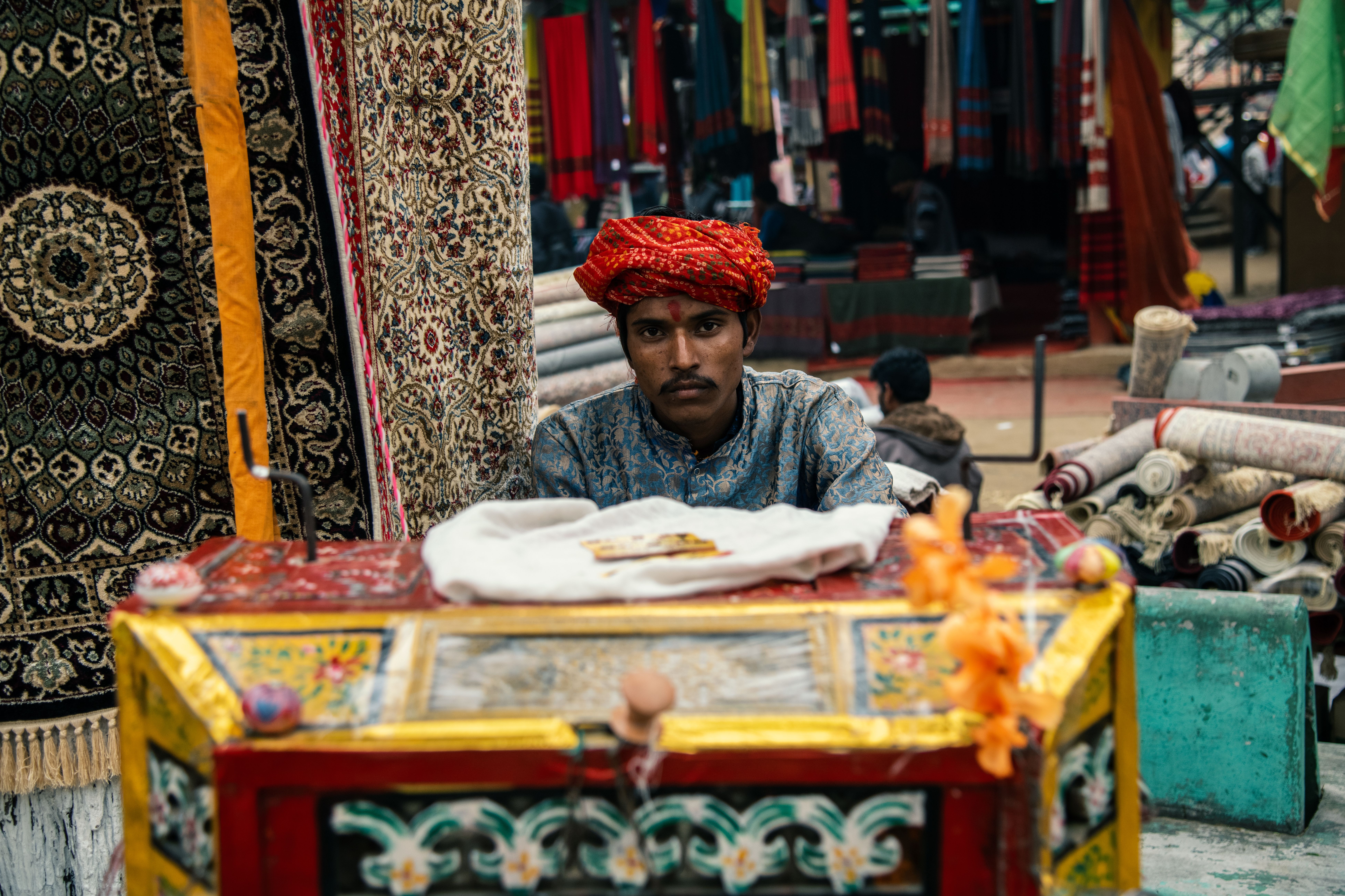 Indian Bazaar Vendor with Traditional Rugs · Free Stock Photo