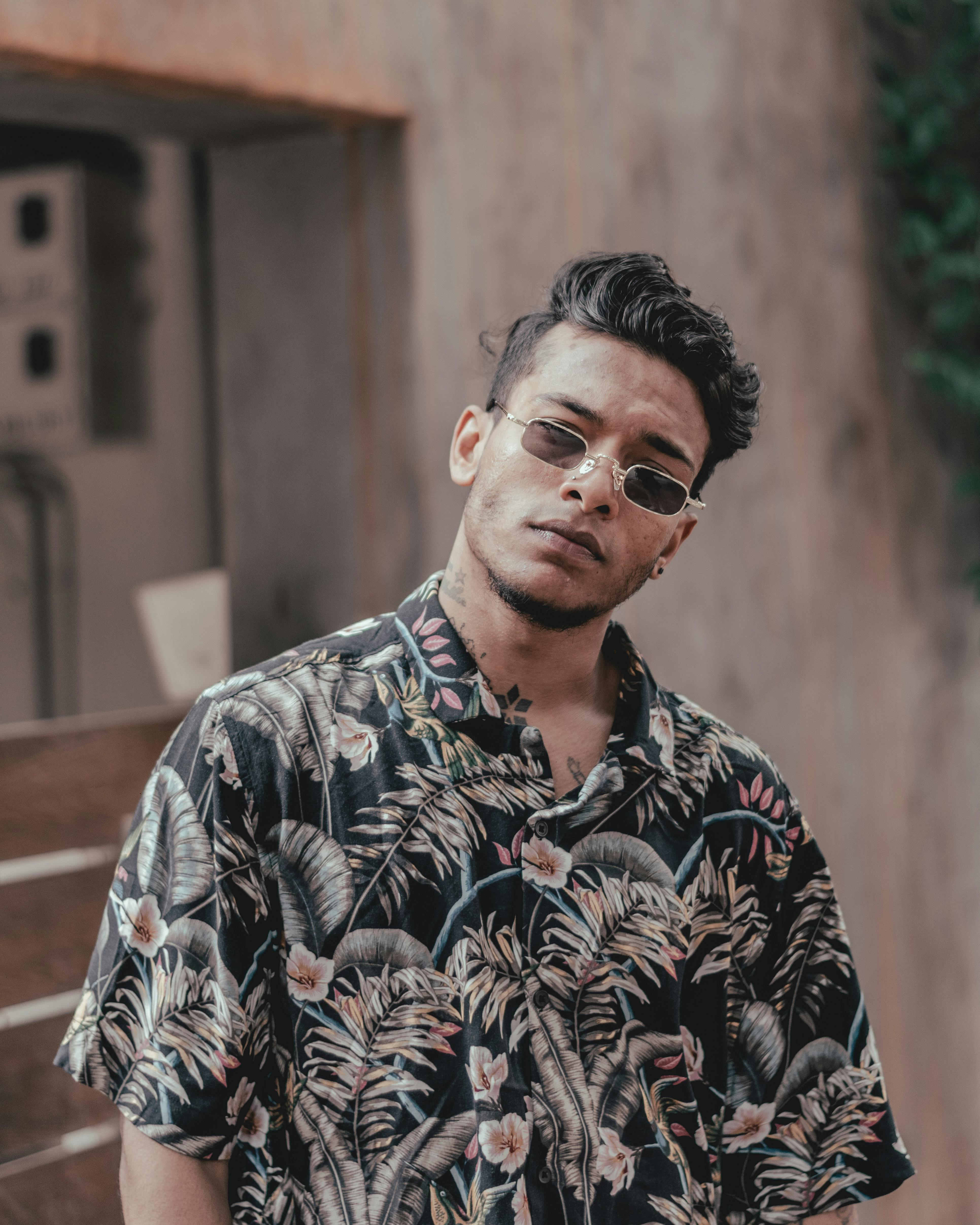 一位时尚男士身着花卉衬衫，戴着墨镜，尽显现代休闲风尚