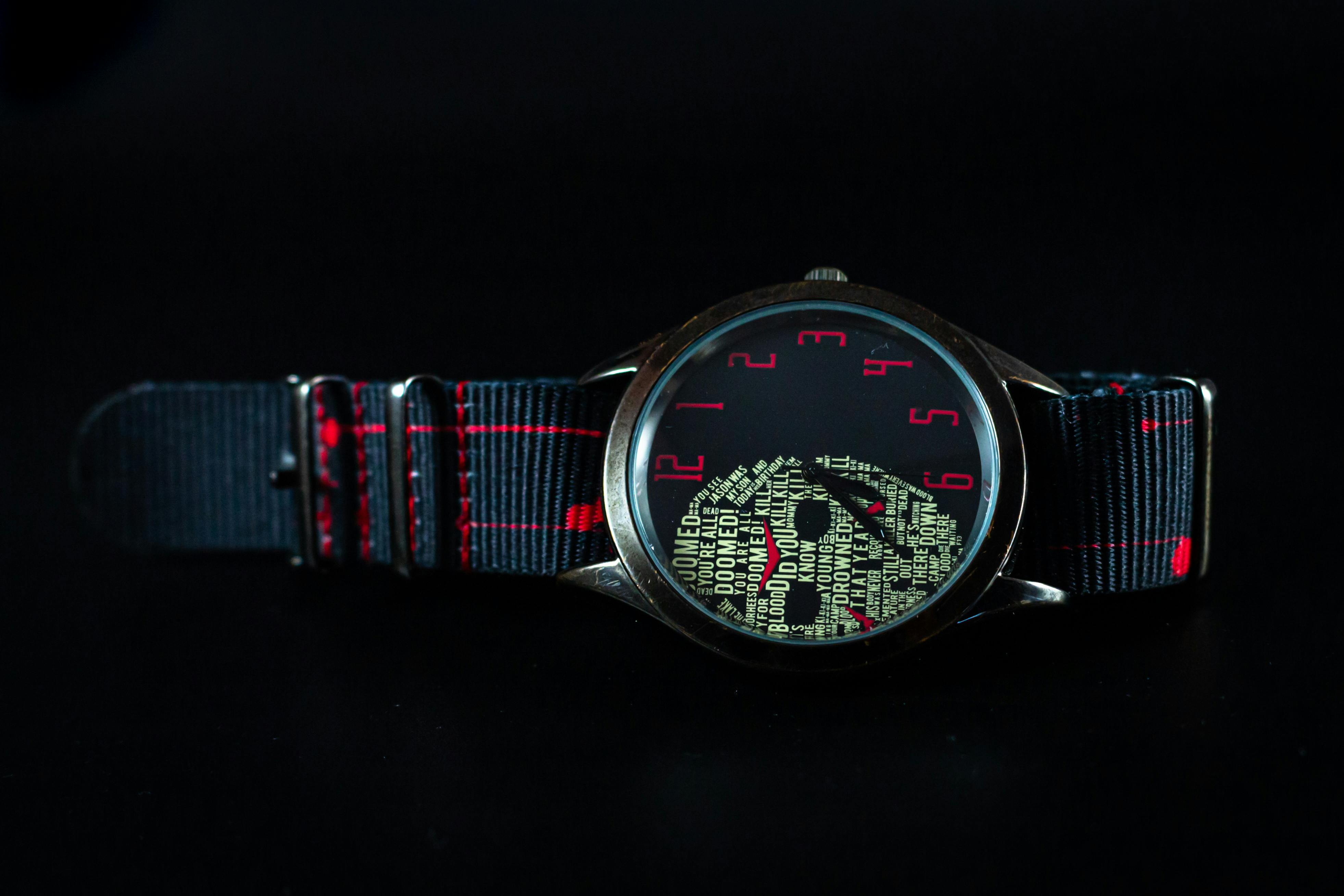 Free Elegant wristwatch featuring a textured dial and sleek black fabric strap with red stitching, perfect for fashion enthusiasts. Stock Photo