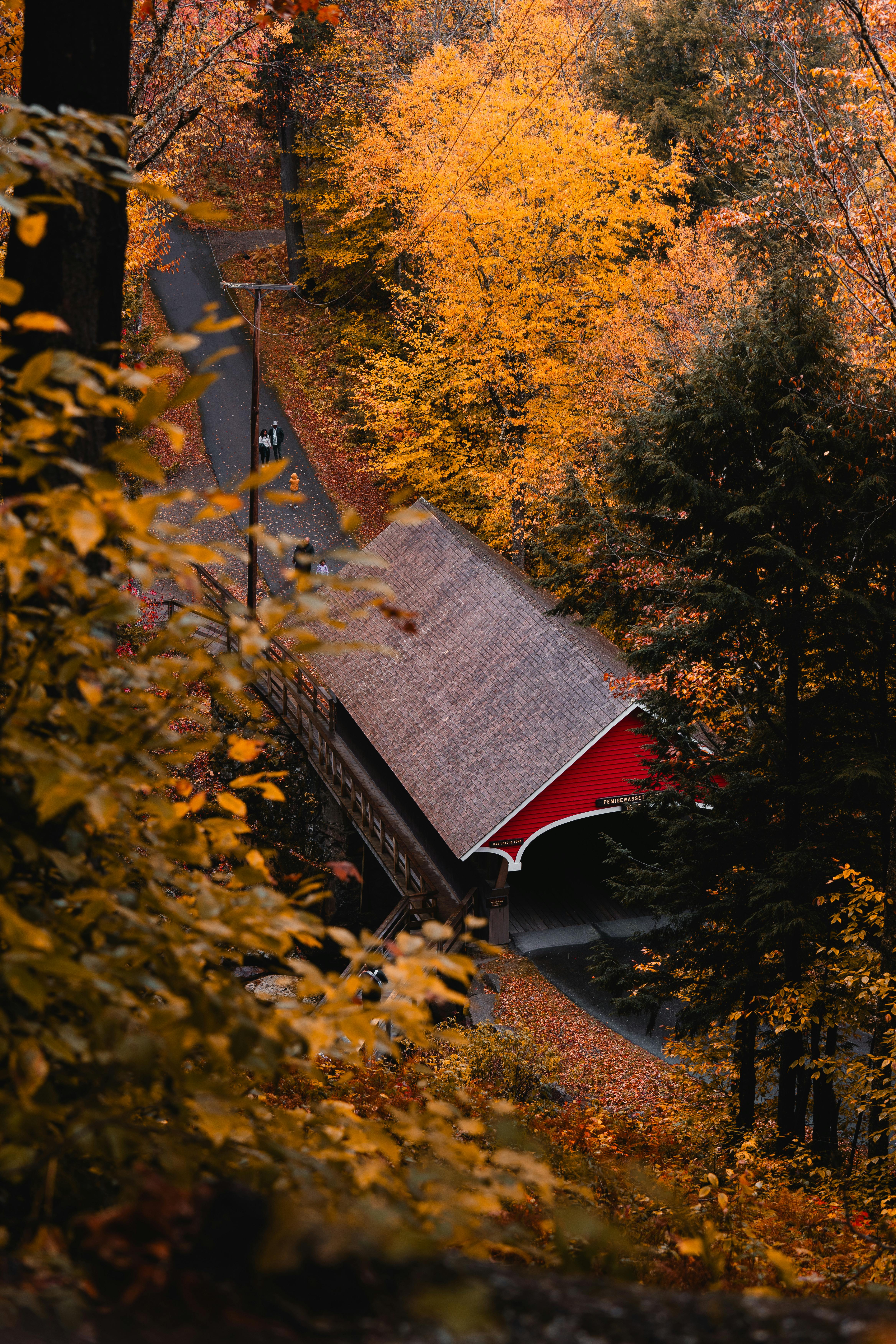 A beautiful autumn scene featuring a red covered bridge surrounded by vibrant fall foliage in Lincoln, New Hampshire.